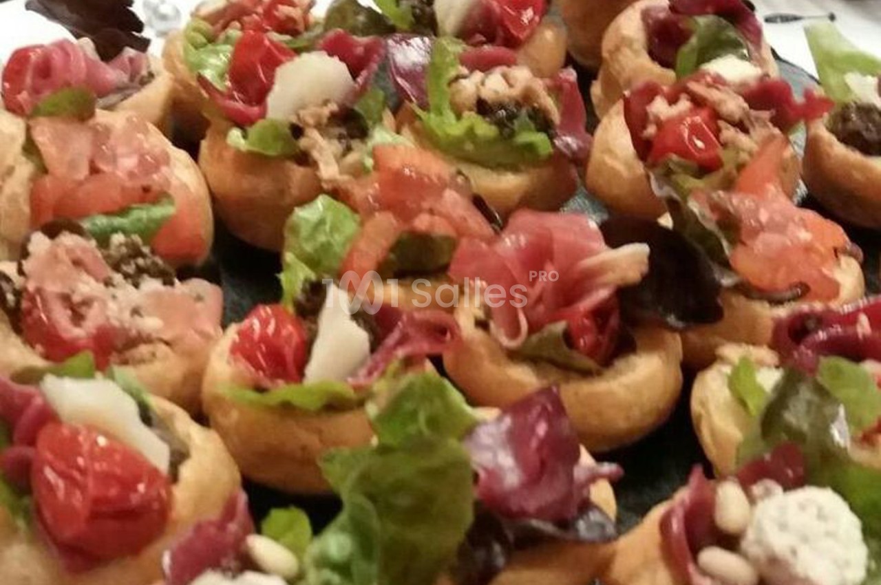 Assortiment de bouchées garnies de légumes, charcuterie, fromage et salade sur un plateau.