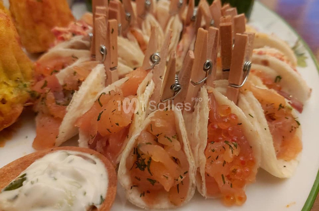 Mini-tacos garnis de saumon fumé, aneth et œufs de poisson, maintenus par des pinces en bois sur une assiette.