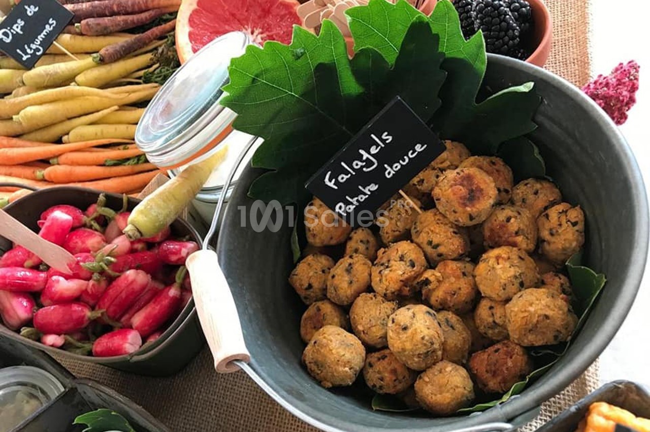 Boules de falafels à la patate douce dans un bol en métal, entourées de légumes frais et de fruits.