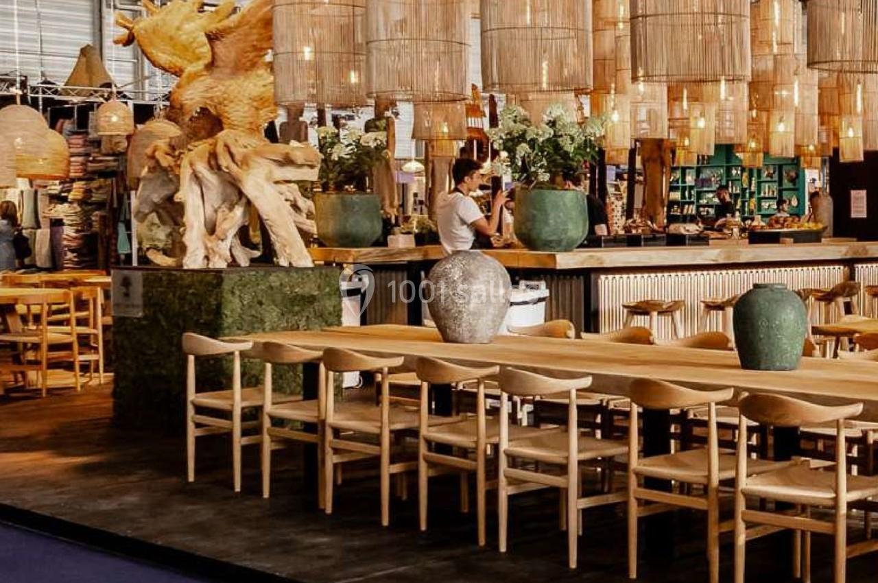 Salle de restaurant avec un long comptoir, des chaises en bois, des luminaires suspendus et une sculpture décorative.