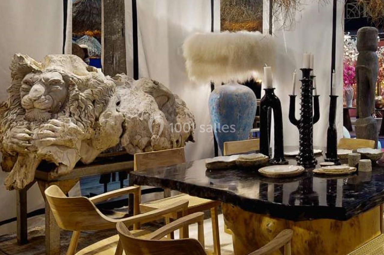 Salle décorée avec une table en bois, des chaises, un grand vase bleu, un chandelier noir et une sculpture de lion.