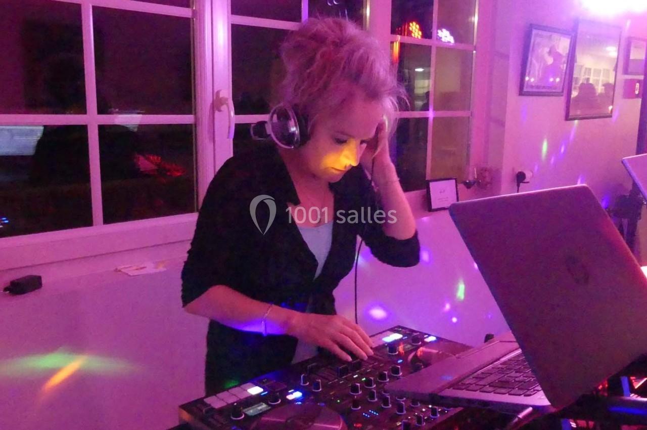 Une femme mixe de la musique sur une console DJ dans une pièce éclairée par des lumières colorées.