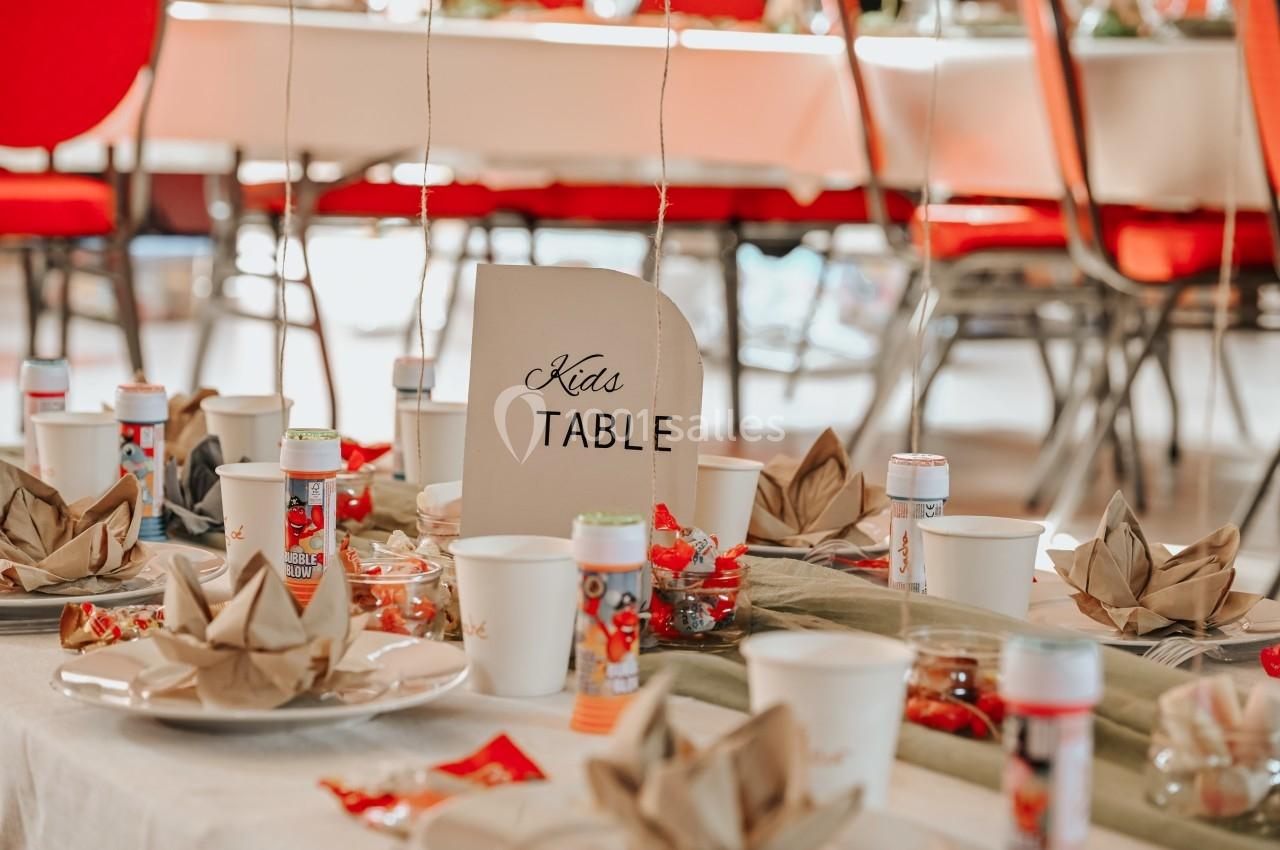 Table décorée pour enfants avec assiettes, gobelets, serviettes pliées, bonbons et pancarte ’Kids Table’.