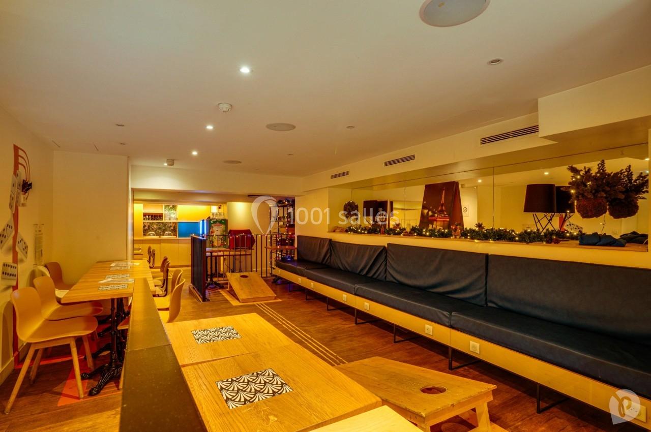 Salle lumineuse avec tables en bois, chaises modernes, banquette bleue et décorations murales dans un espace convivial.