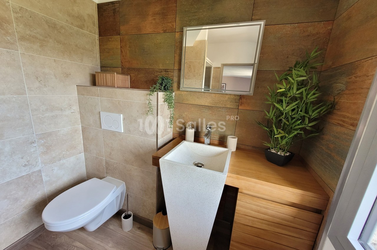 Salle de bain moderne avec toilettes suspendues, lavabo design, meuble en bois et plantes décoratives.