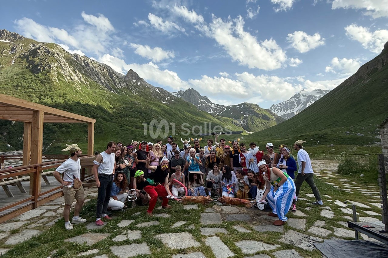Un grand groupe de personnes déguisées posant en extérieur dans un paysage de montagne verdoyant.