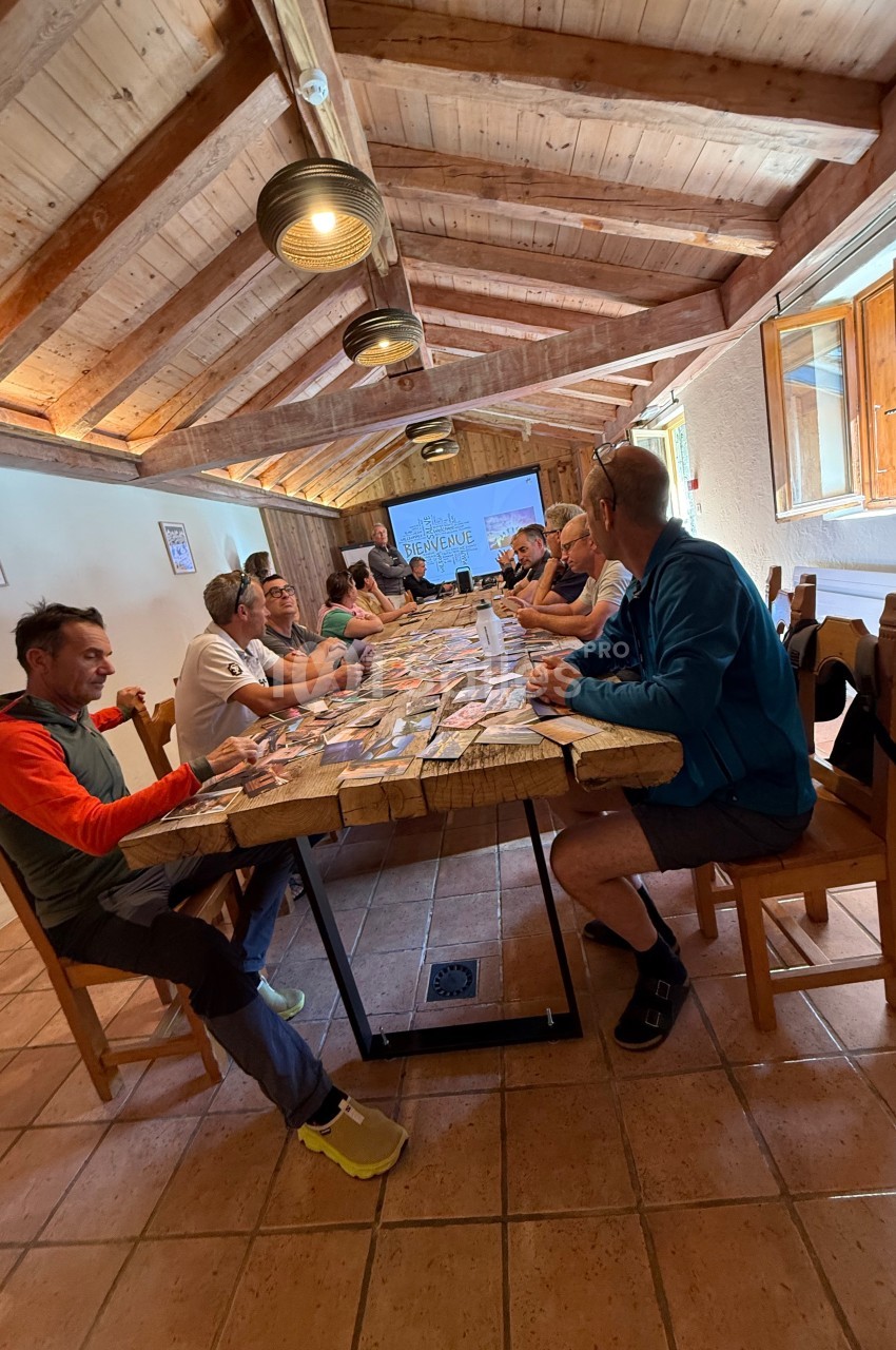 Des personnes assises autour d'une table en bois dans une salle lumineuse, discutant devant des documents étalés.
