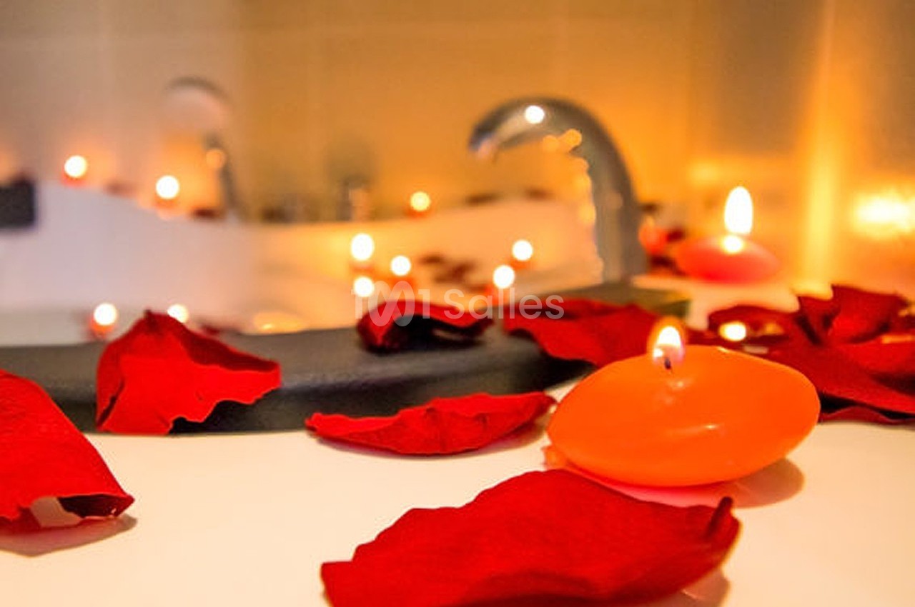 Pétales de rose et bougies allumées disposés autour d'une baignoire dans une ambiance chaleureuse.