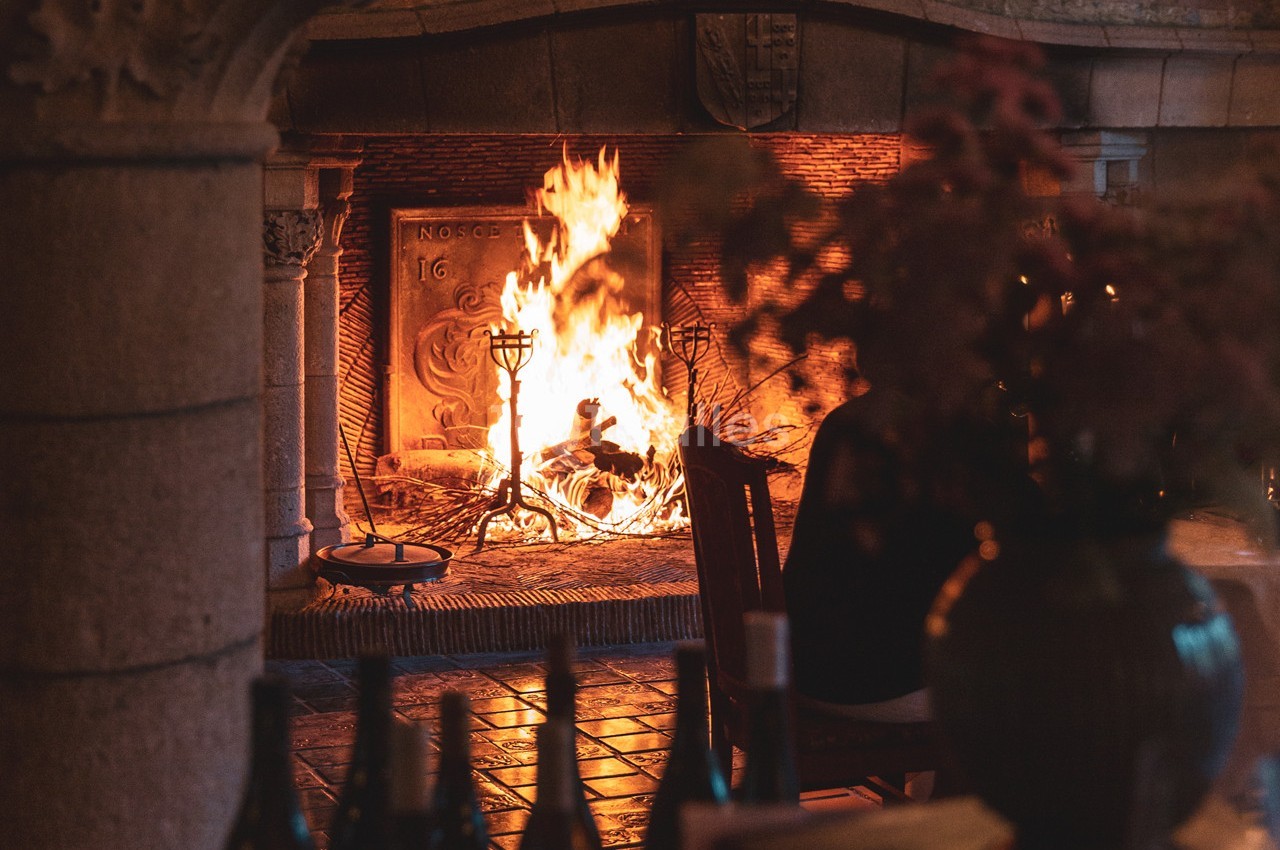 Cheminée en pierre avec un feu de bois allumé, éclairant une pièce chaleureuse avec des objets décoratifs au premier plan.