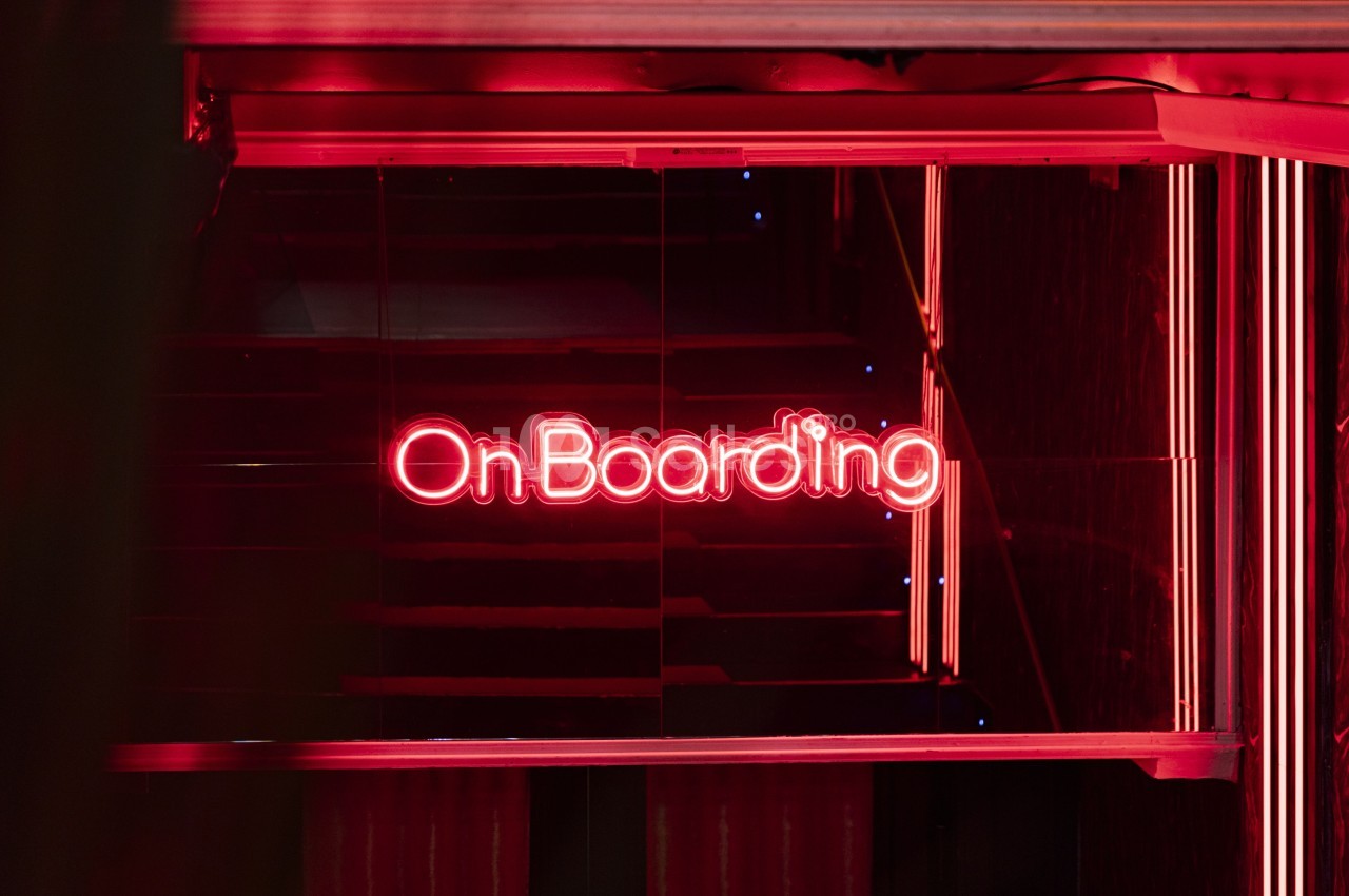 Enseigne lumineuse rouge avec le mot ’OnBoarding’ visible dans un environnement sombre et moderne.