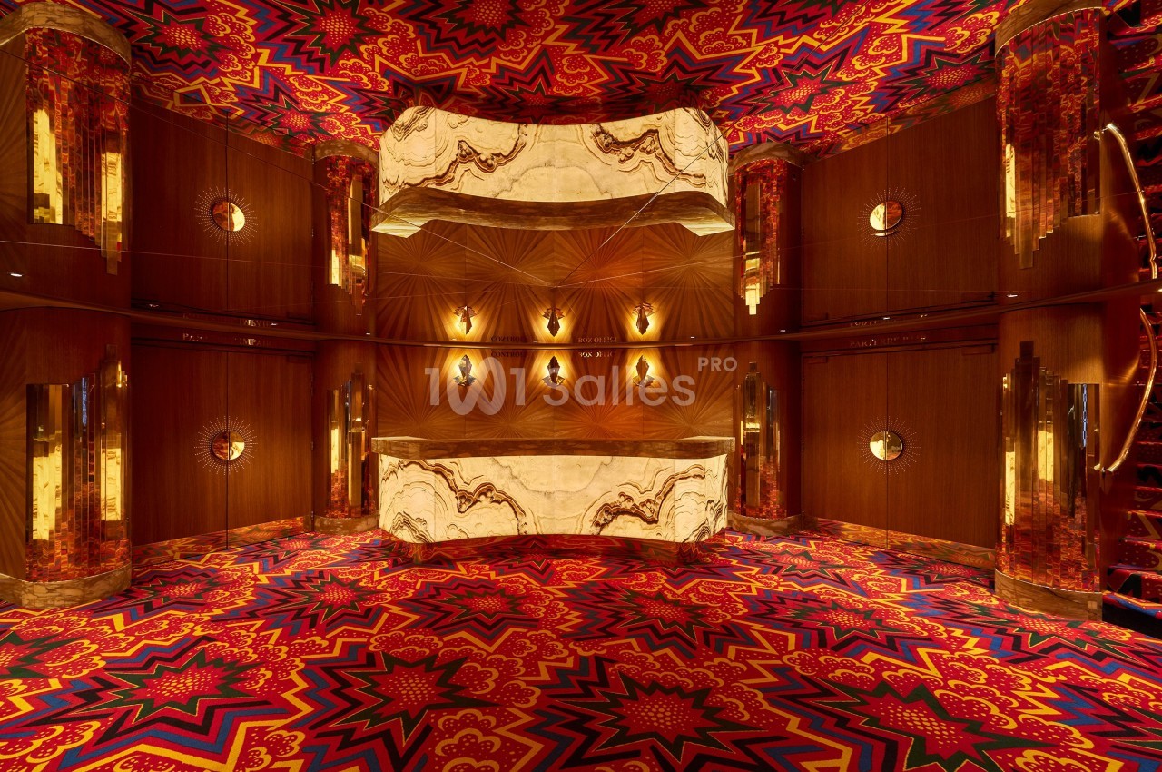 Intérieur d'une pièce aux motifs colorés et symétriques avec des murs en bois, des miroirs et un plafond lumineux.