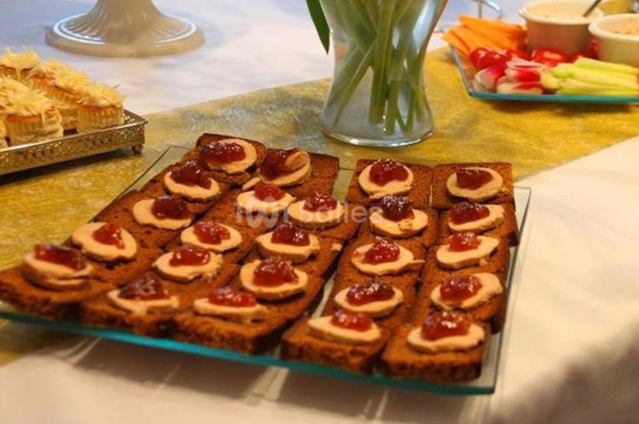 Plateau de toasts garnis de sauce et de condiments, disposé sur une table avec d'autres amuse-bouches et décorations.