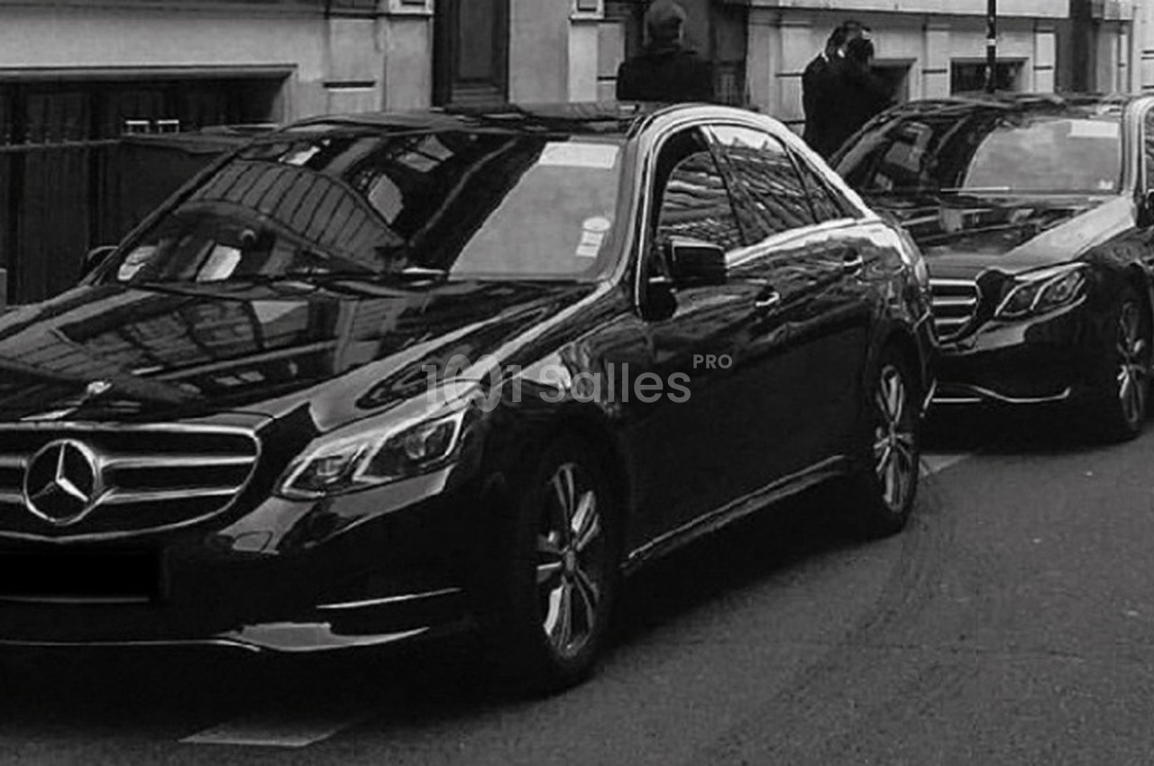 Deux voitures noires de marque Mercedes garées en file sur une rue urbaine.