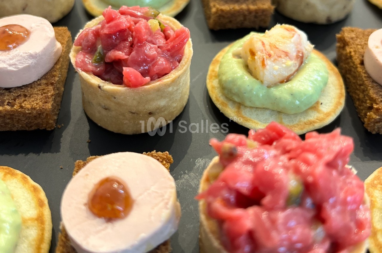 Assortiment de canapés variés avec tartare, mousse de foie et crème verte sur différentes bases.