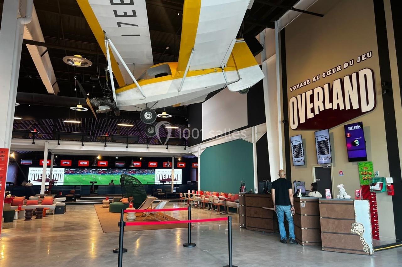 Avion suspendu dans un espace intérieur moderne avec comptoir, écrans et zone de détente aménagée.