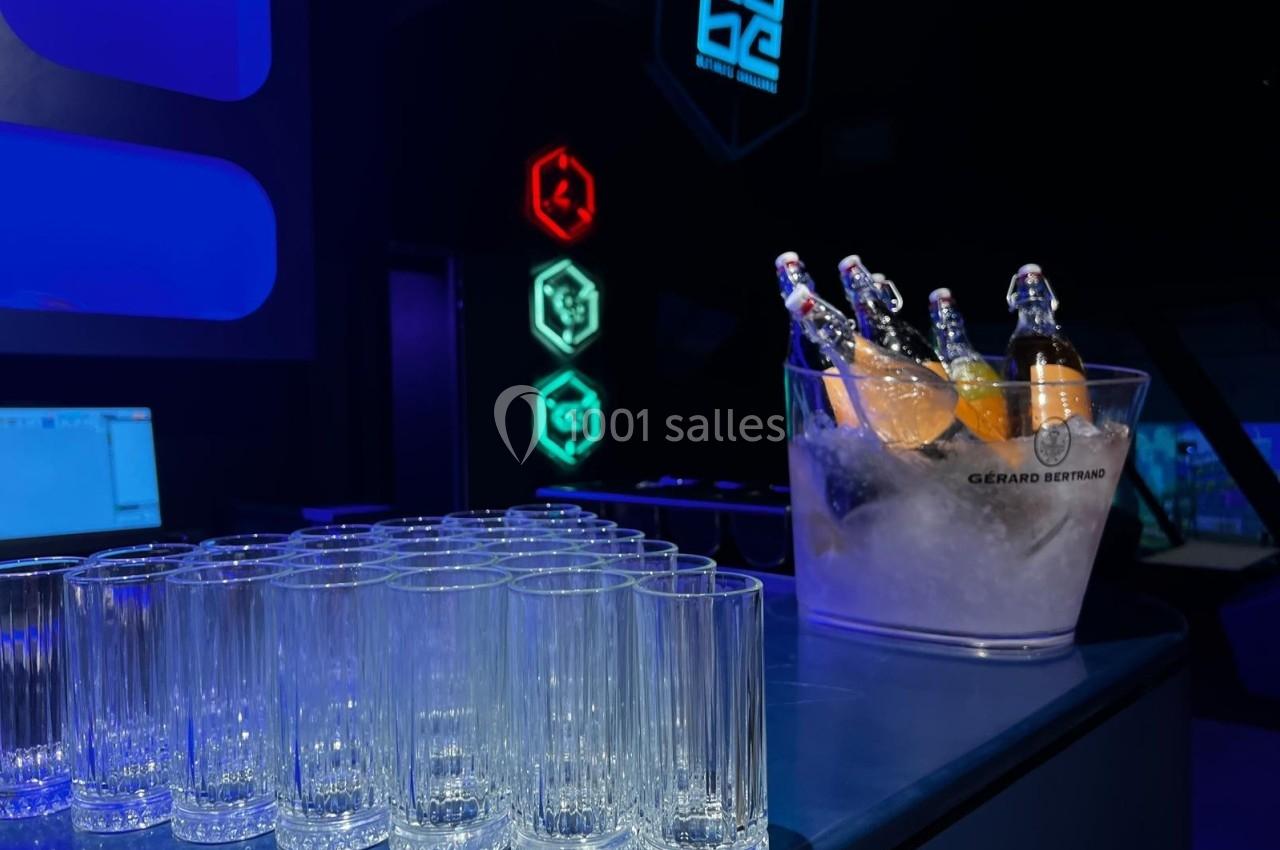 Verres vides alignés sur un comptoir avec un seau rempli de bouteilles dans un décor lumineux et moderne.