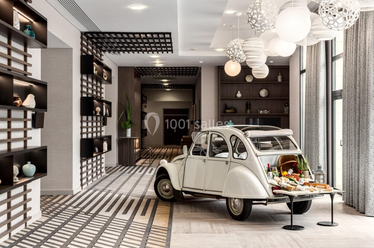 Une voiture ancienne blanche exposée dans un hall moderne, utilisée comme présentoir pour des produits alimentaires.