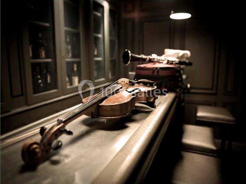 Un violon et une clarinette posés sur une table en bois dans une pièce faiblement éclairée.