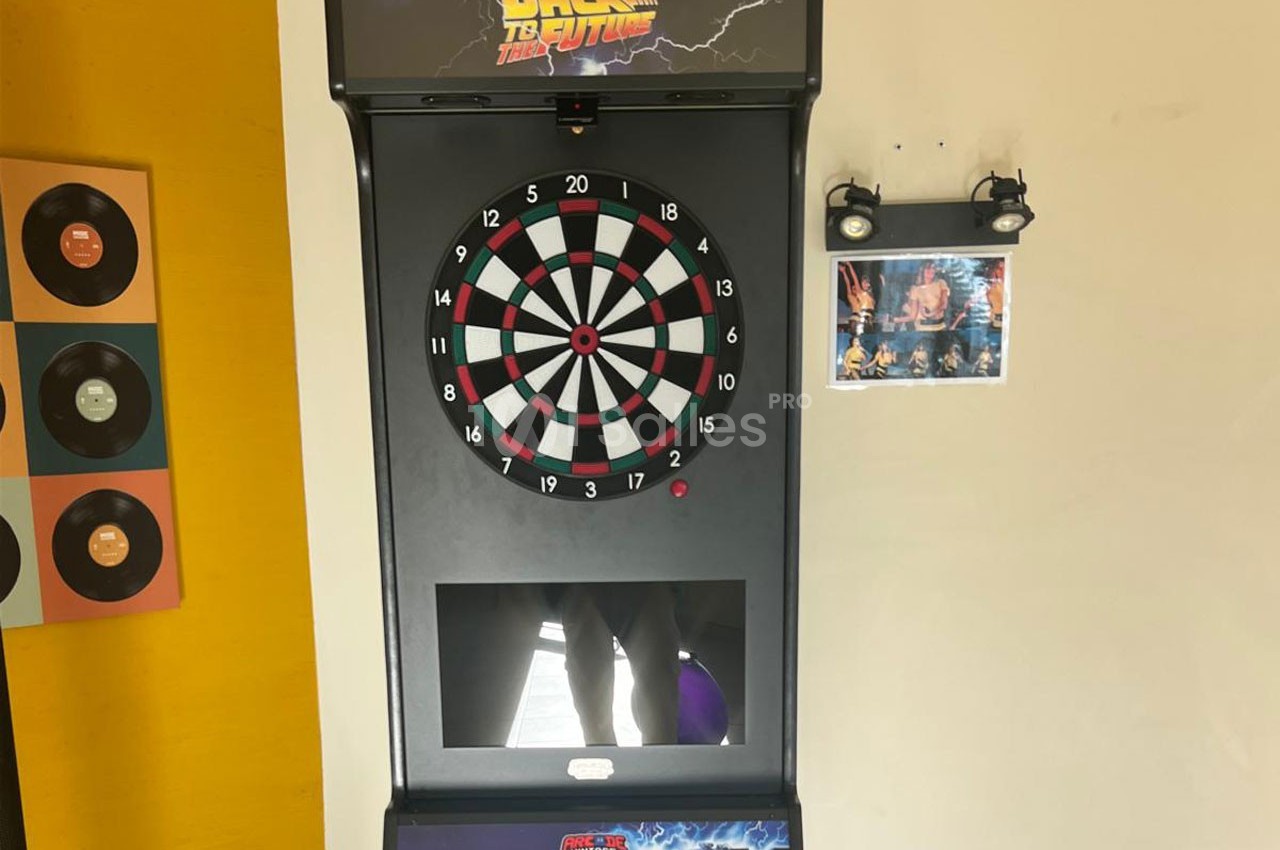 Jeu de fléchettes électronique avec écran intégré, décoré d'éléments rétro et d'une affiche de film.