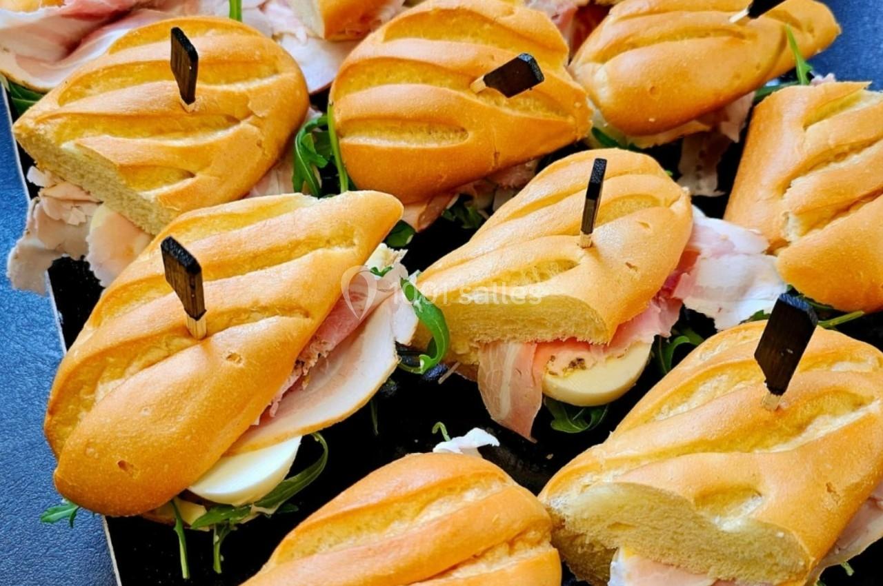 Plateau de mini-sandwichs garnis de jambon, œufs durs, roquette et servis sur pain doré.