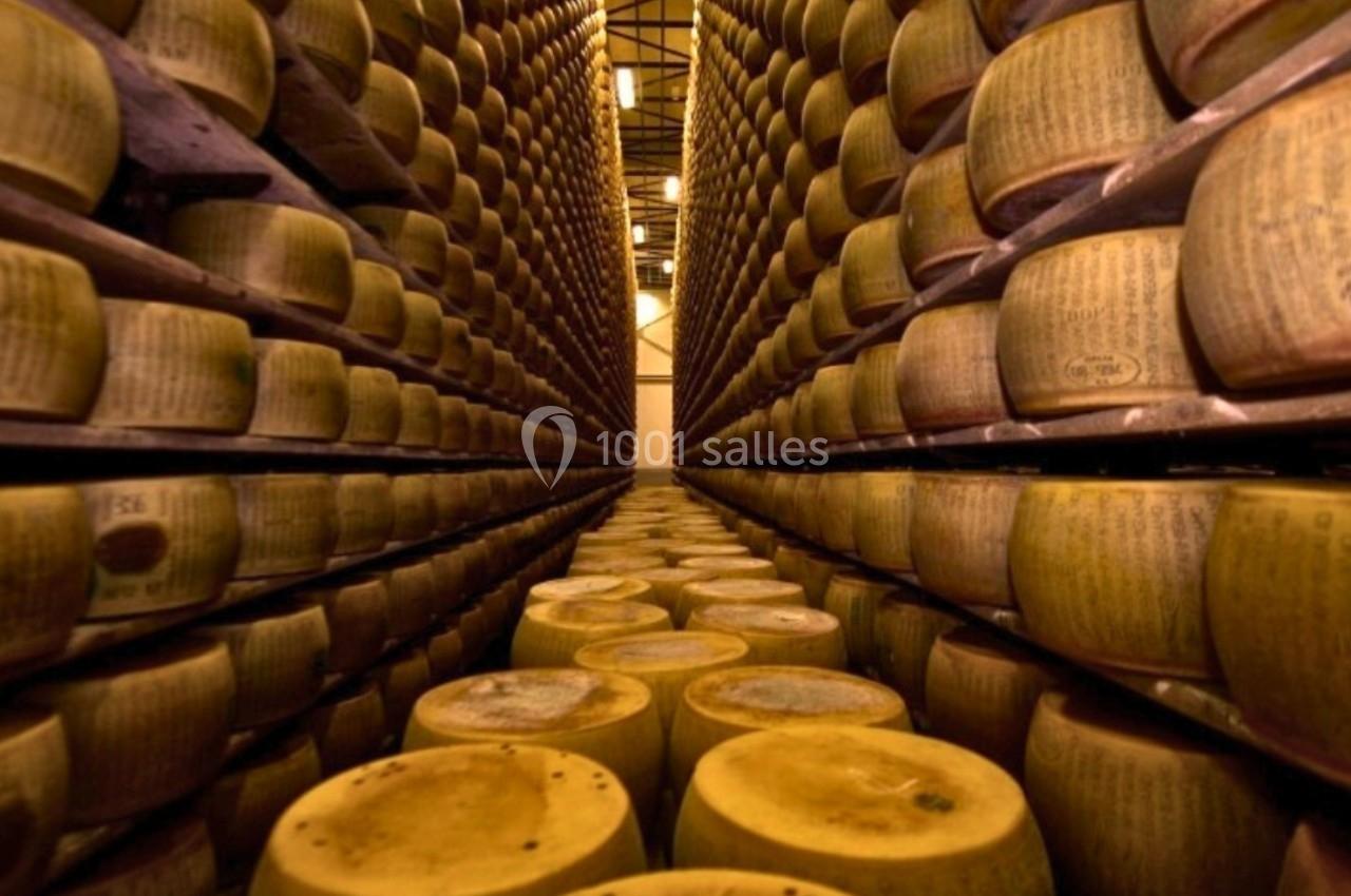 Rangées de meules de fromage entreposées dans un vaste espace de stockage industriel.