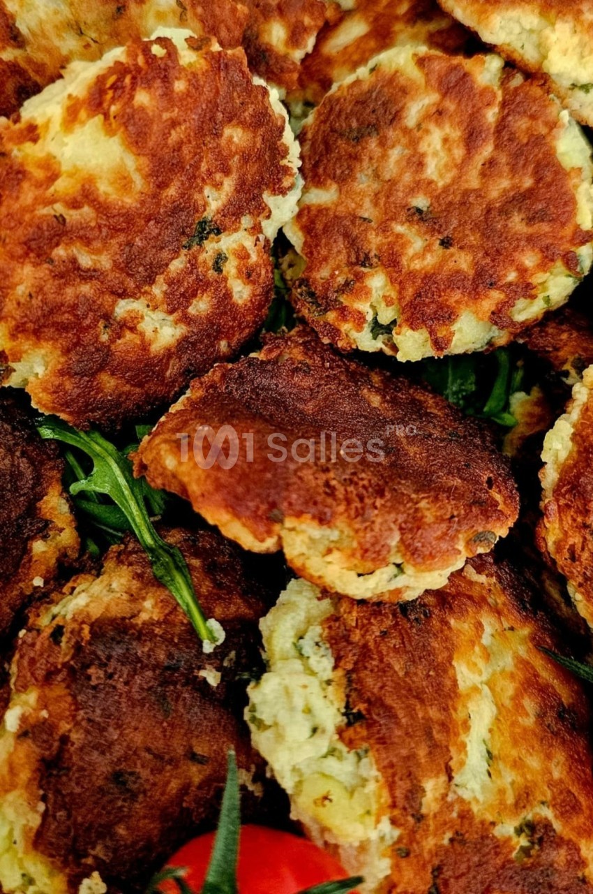 Galettes dorées aux herbes disposées sur un lit de roquette avec quelques tomates cerises.