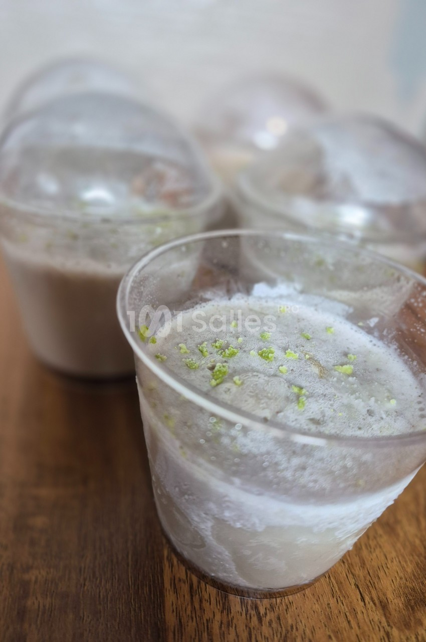Desserts glacés en gobelets transparents, garnis de zestes verts, posés sur une table en bois.