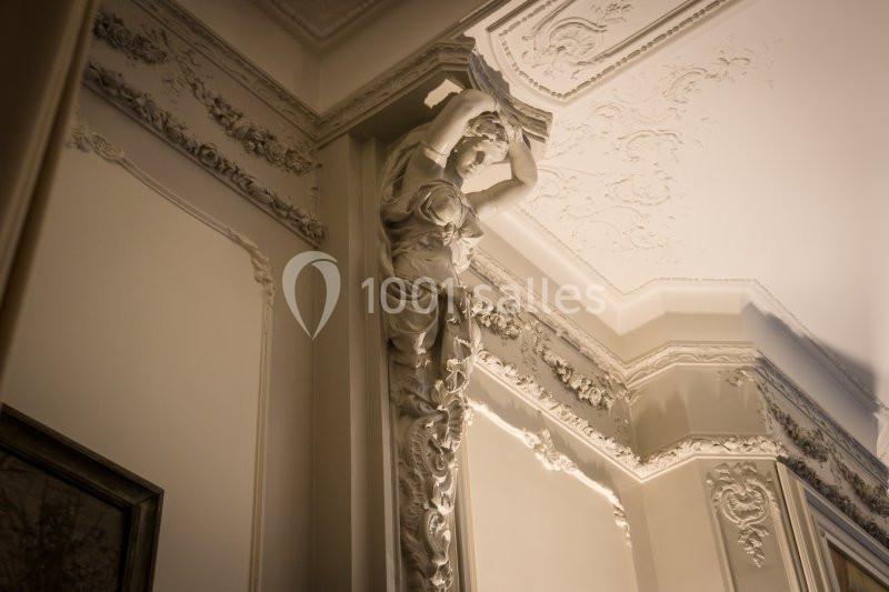 Sculpture ornementale en relief représentant une figure féminine soutenant un plafond richement décoré.