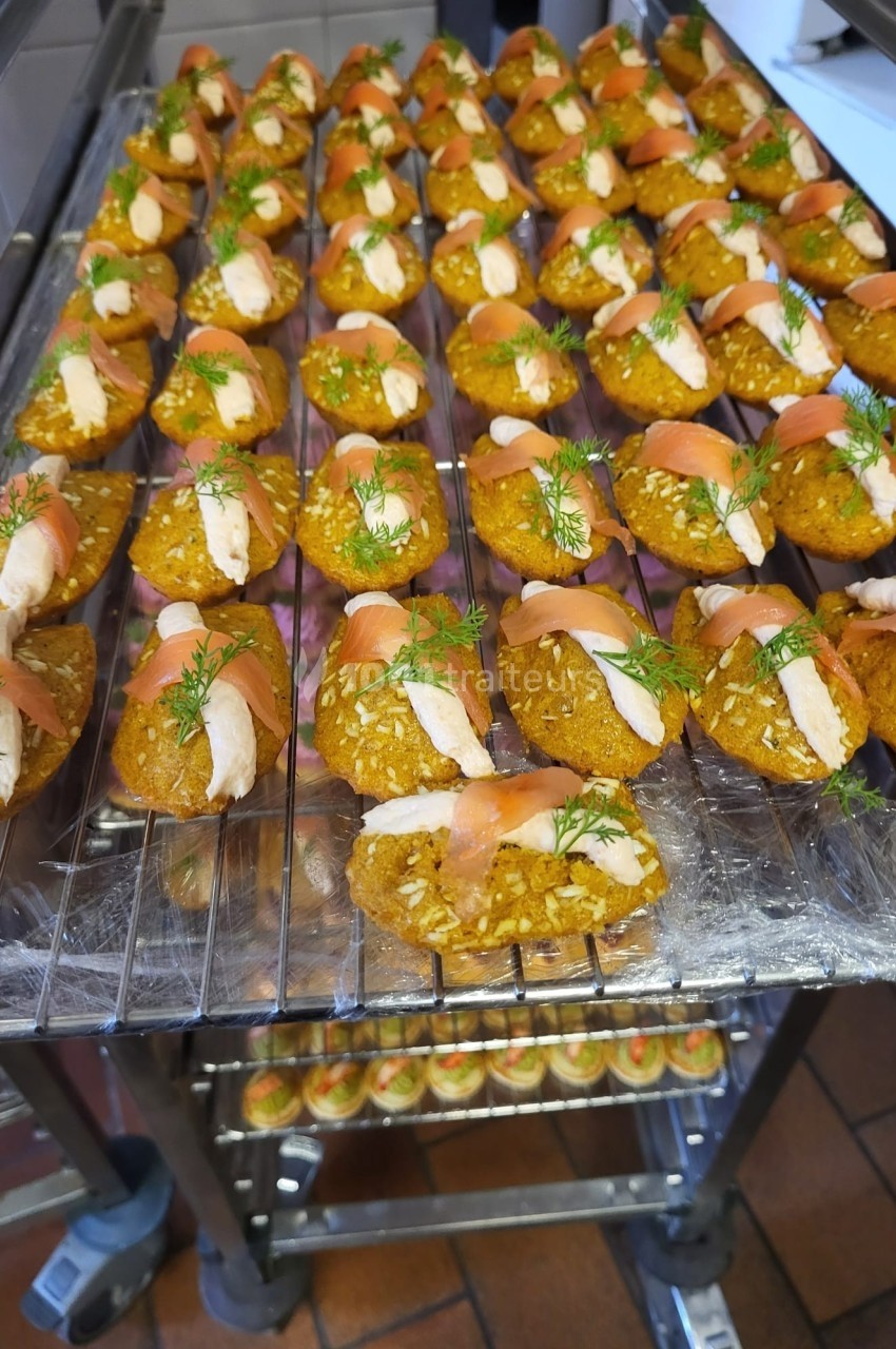 Plateau de bouchées apéritives à base de saumon fumé, crème et herbes fraîches, disposées sur une grille.
