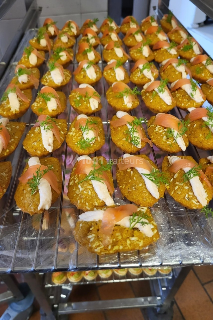 Bouchées apéritives alignées sur une grille, composées de saumon fumé, crème et garnies d'aneth.