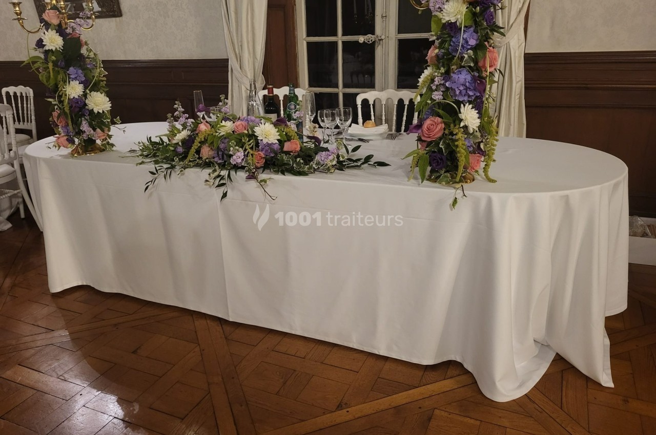 Table décorée de nappes blanches avec des compositions florales colorées et des chandeliers, dans une salle élégante.