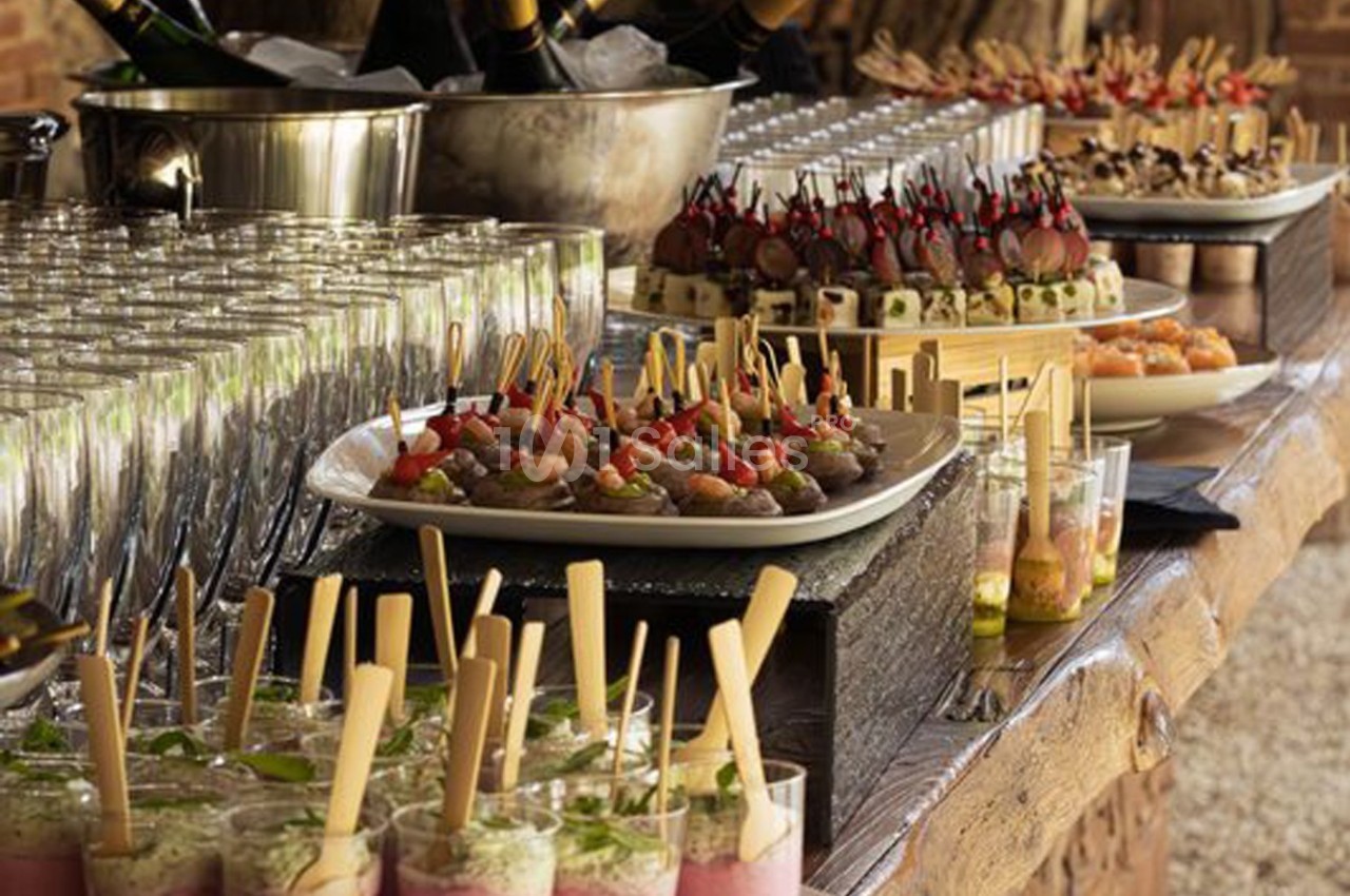 Buffet avec verrines, brochettes apéritives et desserts variés disposés sur une table en bois.