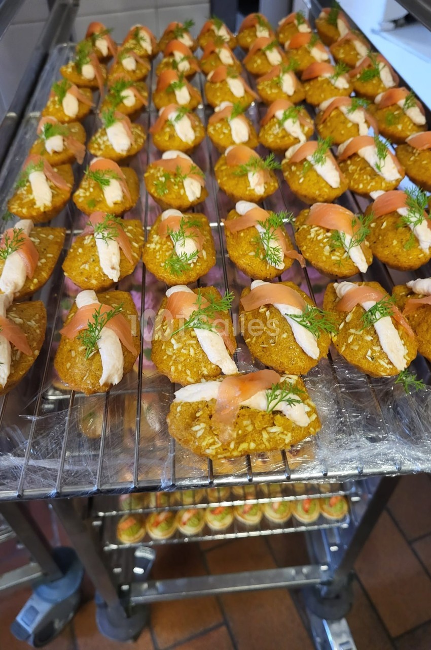 Plateau de bouchées apéritives à base de saumon fumé, crème et aneth, disposées sur une grille en cuisine.