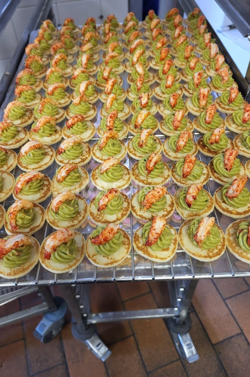 Plateau de bouchées apéritives garnies de mousse verte et de morceaux de crustacés, disposées en rangées.