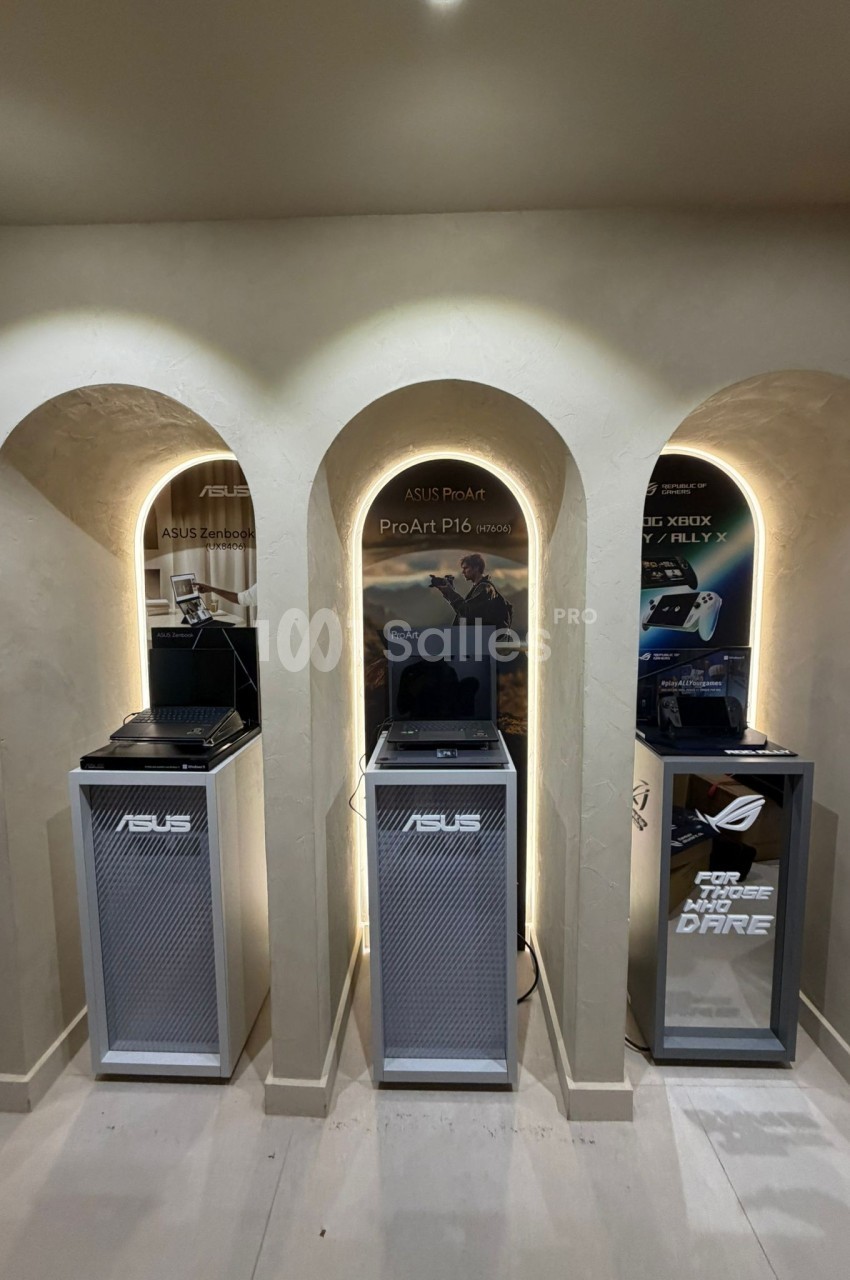 Trois ordinateurs portables exposés dans des niches éclairées, accompagnés de panneaux promotionnels ASUS.