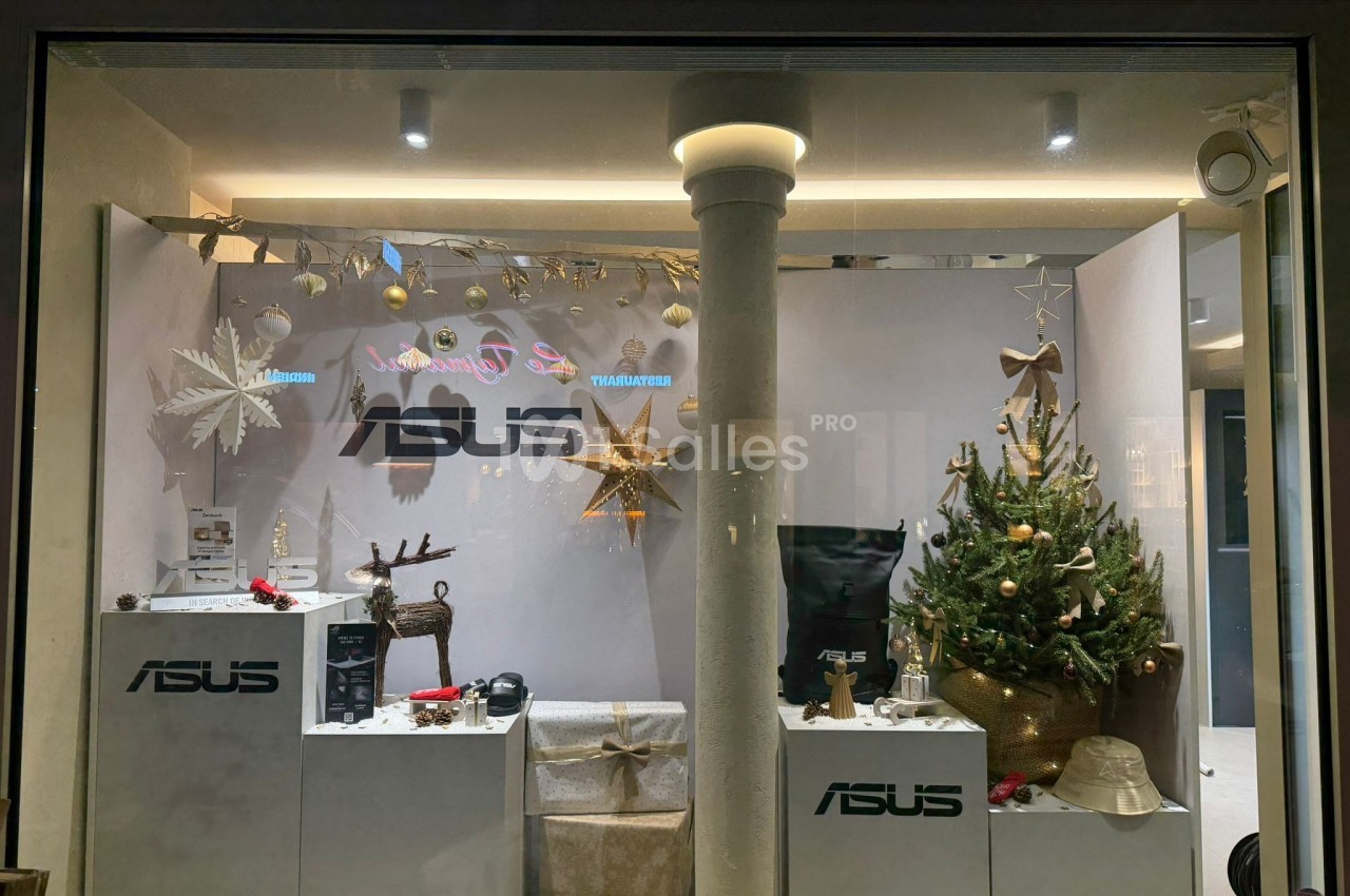 Vitrine décorée pour Noël avec un sapin, des ornements dorés et des produits exposés sur des présentoirs Asus.