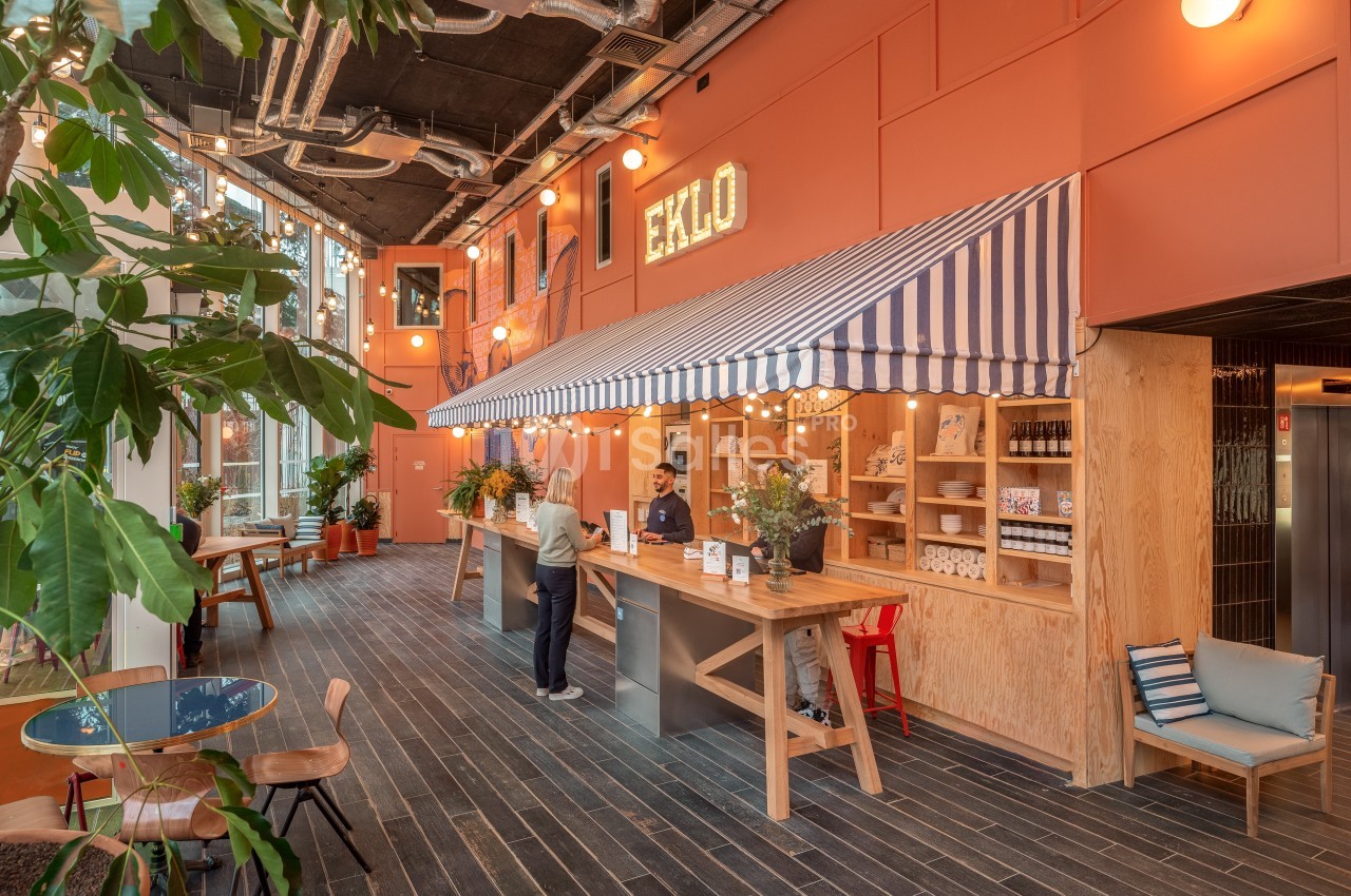 Espace d'accueil lumineux avec un comptoir en bois, une enseigne ’Eklo’, des plantes et une décoration chaleureuse.