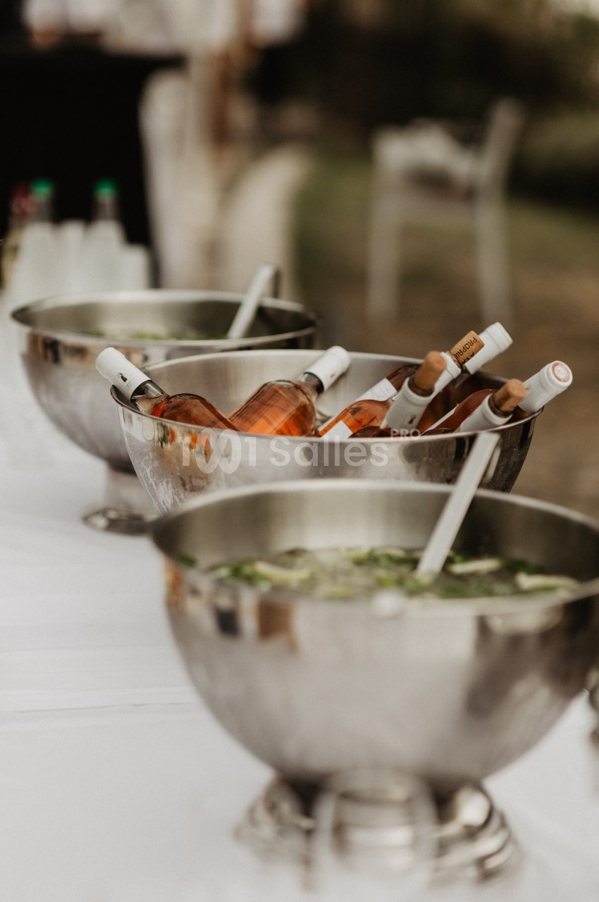 Bouteilles de vin rosé et glaçons dans des seaux en métal sur une table lors d'un événement en extérieur.