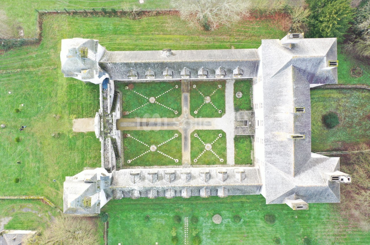 Vue aérienne d'un bâtiment historique entourant un jardin symétrique avec pelouses et allées gravillonnées.