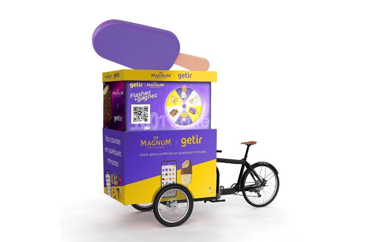 Triporteur promotionnel jaune et violet avec une enseigne Magnum et Getir, affichant un QR code et des visuels de produits.