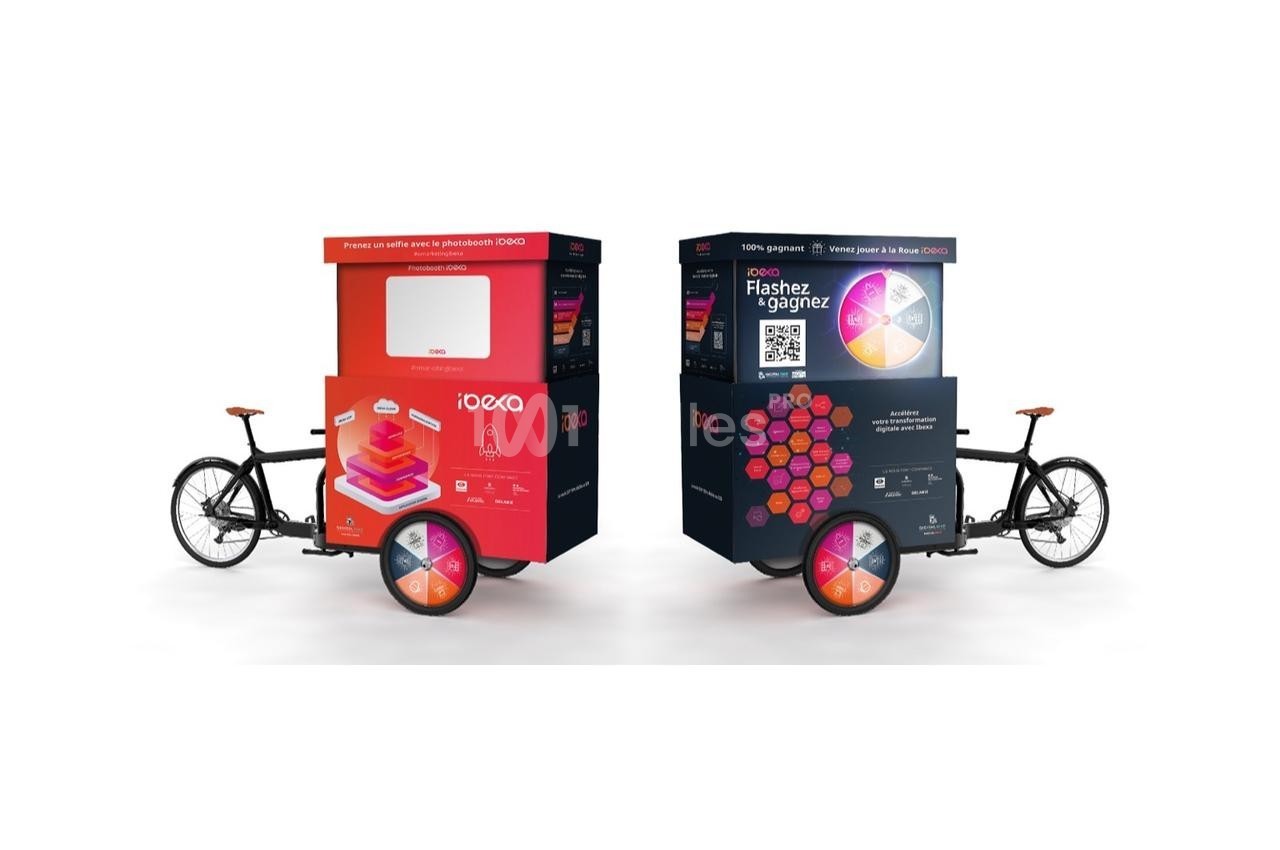 Deux vélos cargo avec des caissons publicitaires colorés, incluant un QR code et des visuels promotionnels.