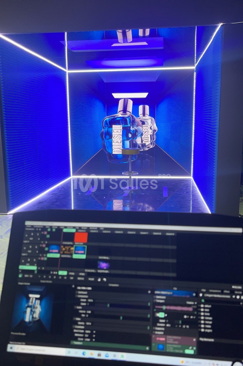 Vue d'un écran de contrôle affichant une scène lumineuse en cube bleu avec des objets au centre.