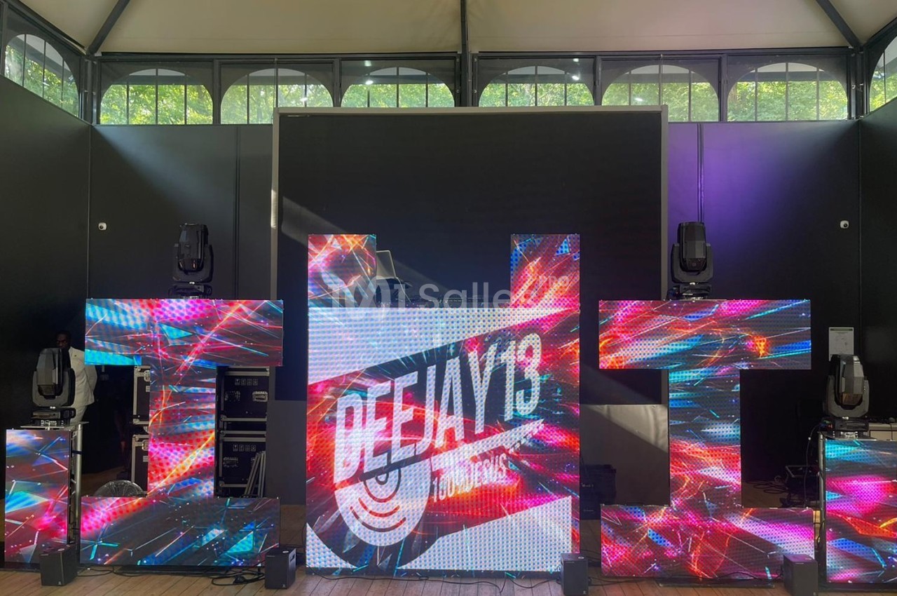 Structure lumineuse avec écrans LED affichant des effets visuels colorés et le logo ’Deejay 13’ dans un espace intérieur.