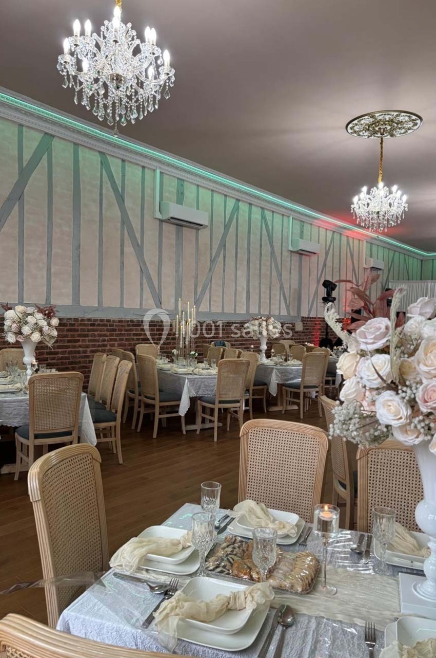 Salle de réception élégante avec tables dressées, décorations florales et chandeliers suspendus.