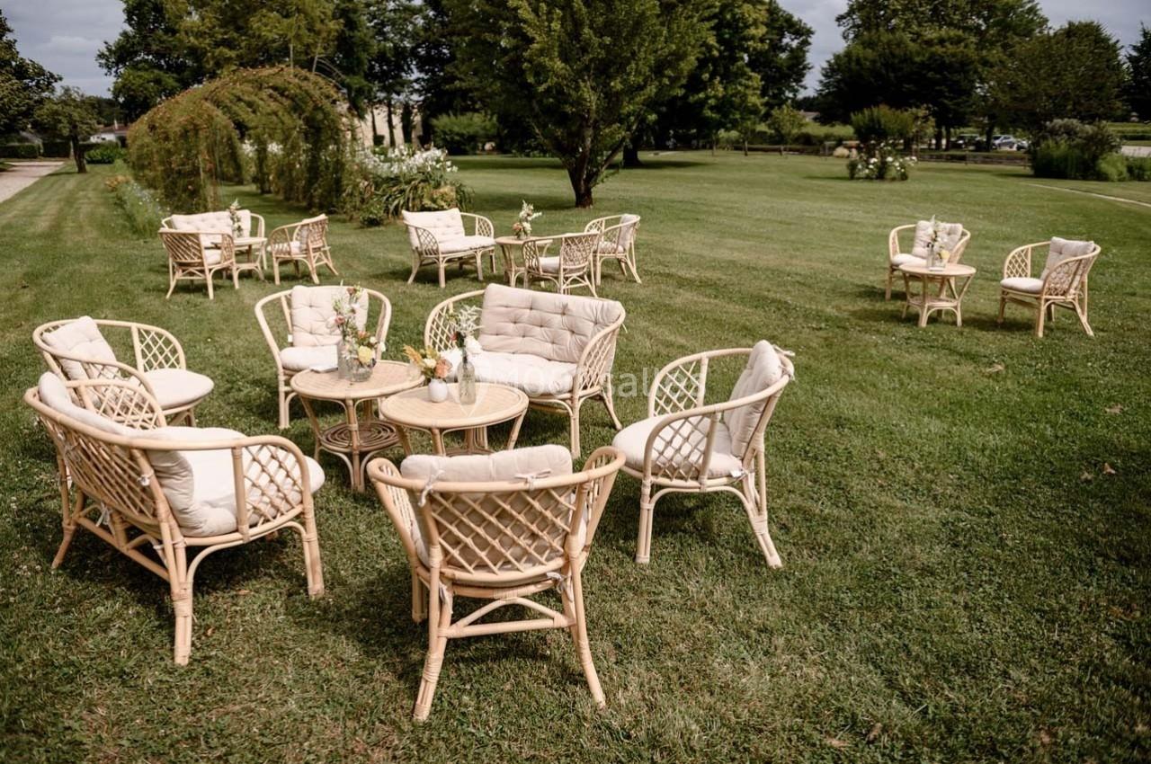 Mobilier en rotin disposé sur une pelouse, formant des espaces de détente avec tables et chaises.