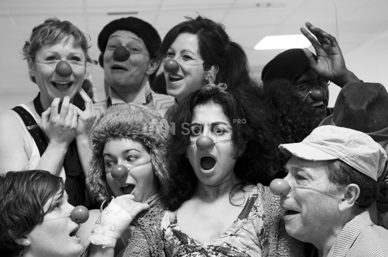 Un groupe de personnes portant des nez rouges de clown, exprimant diverses émotions dans un cadre intérieur.