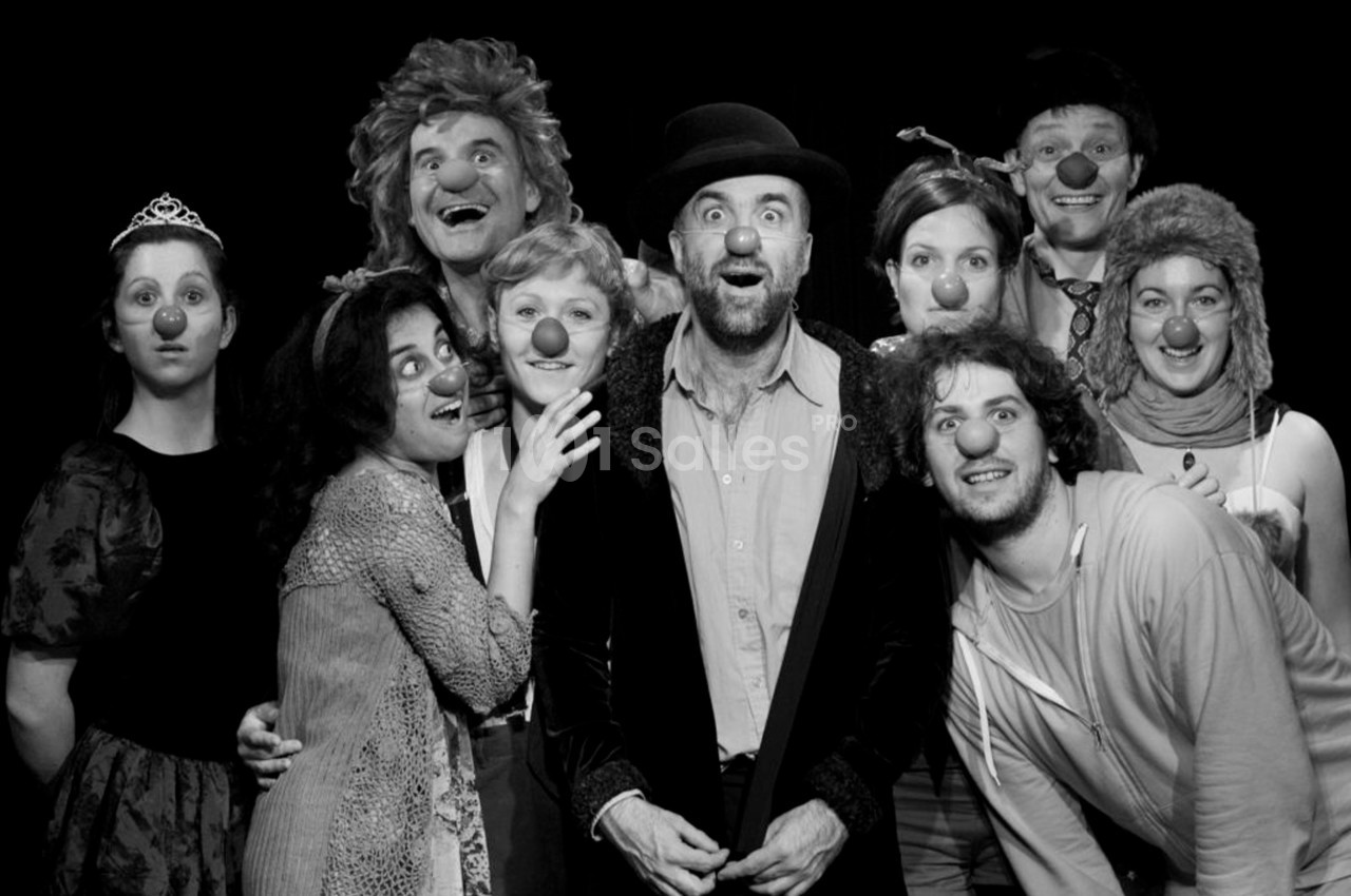 Un groupe de personnes portant des nez rouges de clown pose ensemble sur un fond noir.