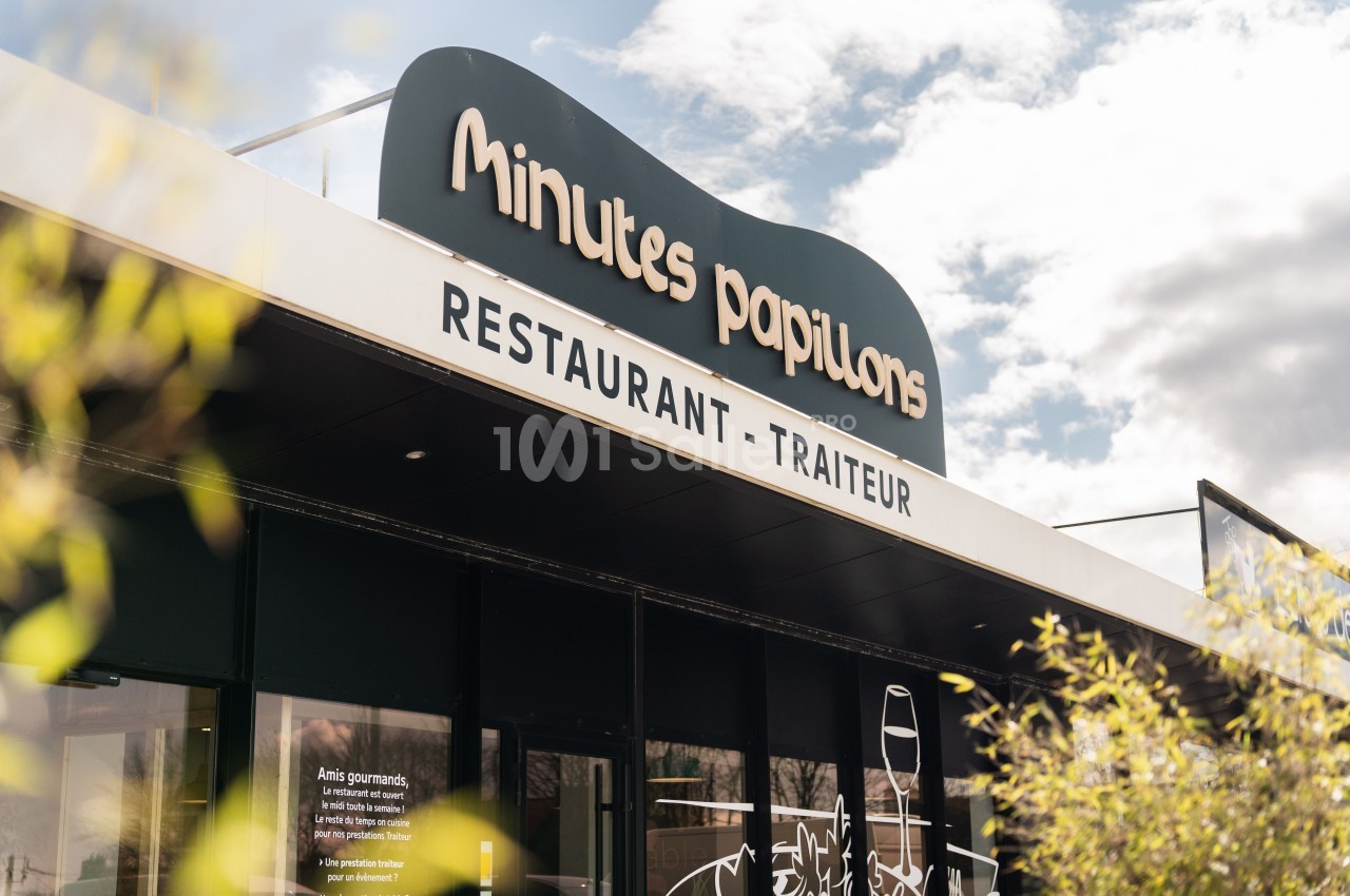 Façade d'un restaurant-traiteur nommé ’Minutes Papillons’, avec un ciel partiellement nuageux en arrière-plan.