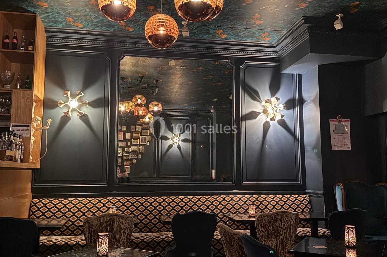 Salle de restaurant cosy avec fauteuils imprimés, éclairage tamisé et plafond décoré de motifs floraux.