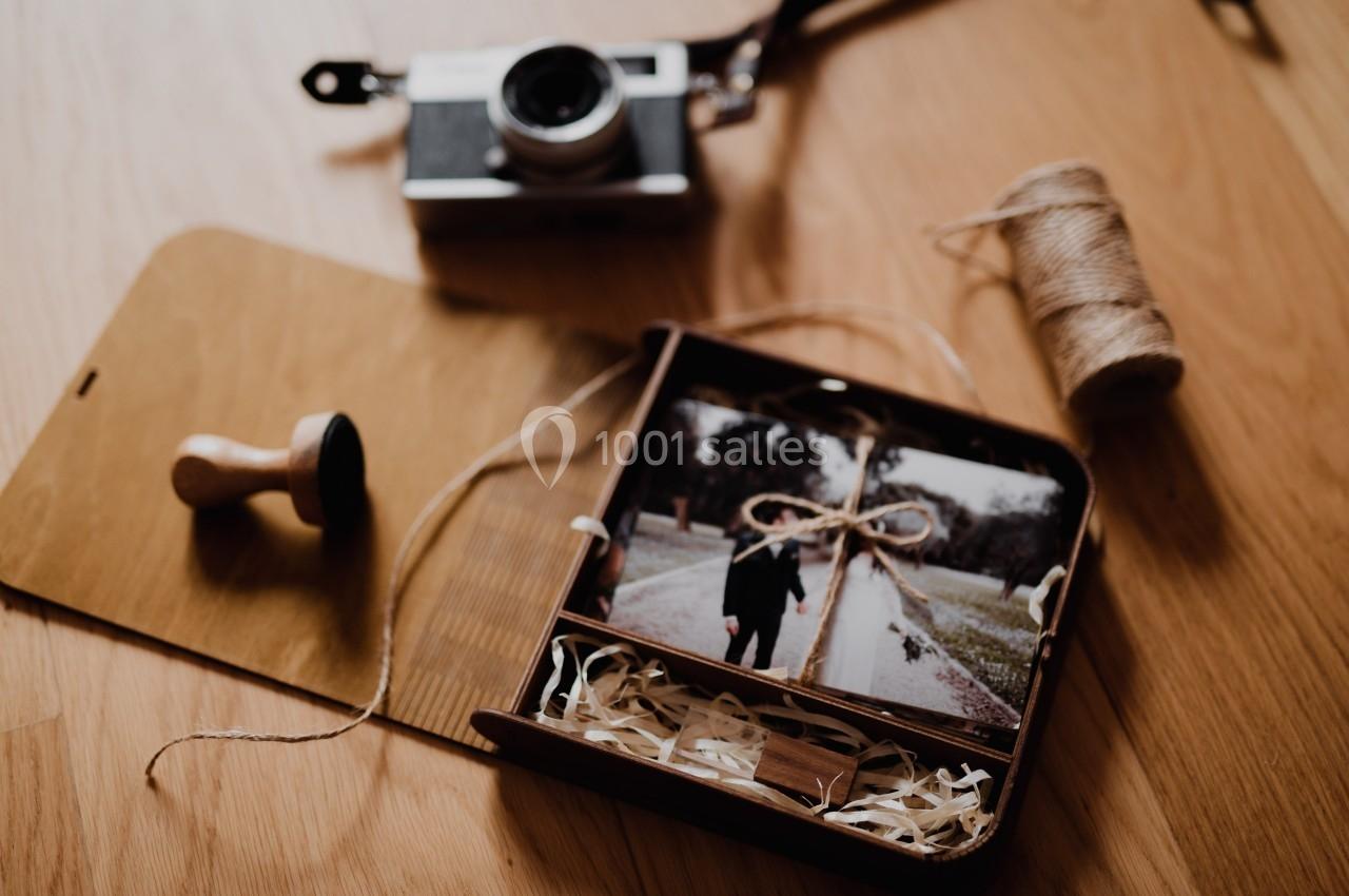 Photo imprimée dans une boîte en bois avec de la ficelle, un tampon, une pellicule et un appareil photo sur une table.